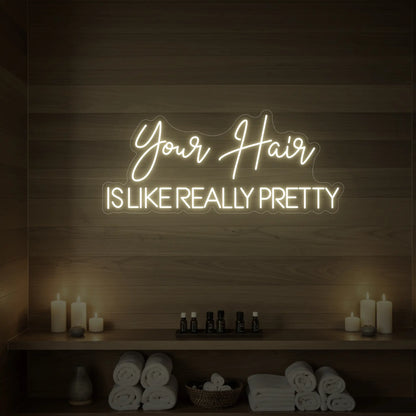 Photo of the 'Your Hair Is Like Really Pretty' neon sign glowing in warm white against a styled interior wall.