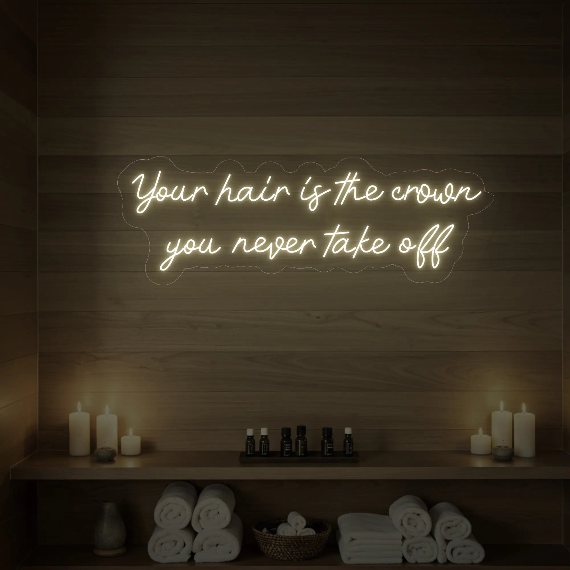 Photo of the 'Your Hair Is The Crown You Never Take Off' neon sign glowing in warm white against a styled interior wall.