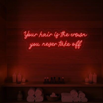 Photo of the 'Your Hair Is The Crown You Never Take Off' neon sign glowing in red against a styled interior wall.