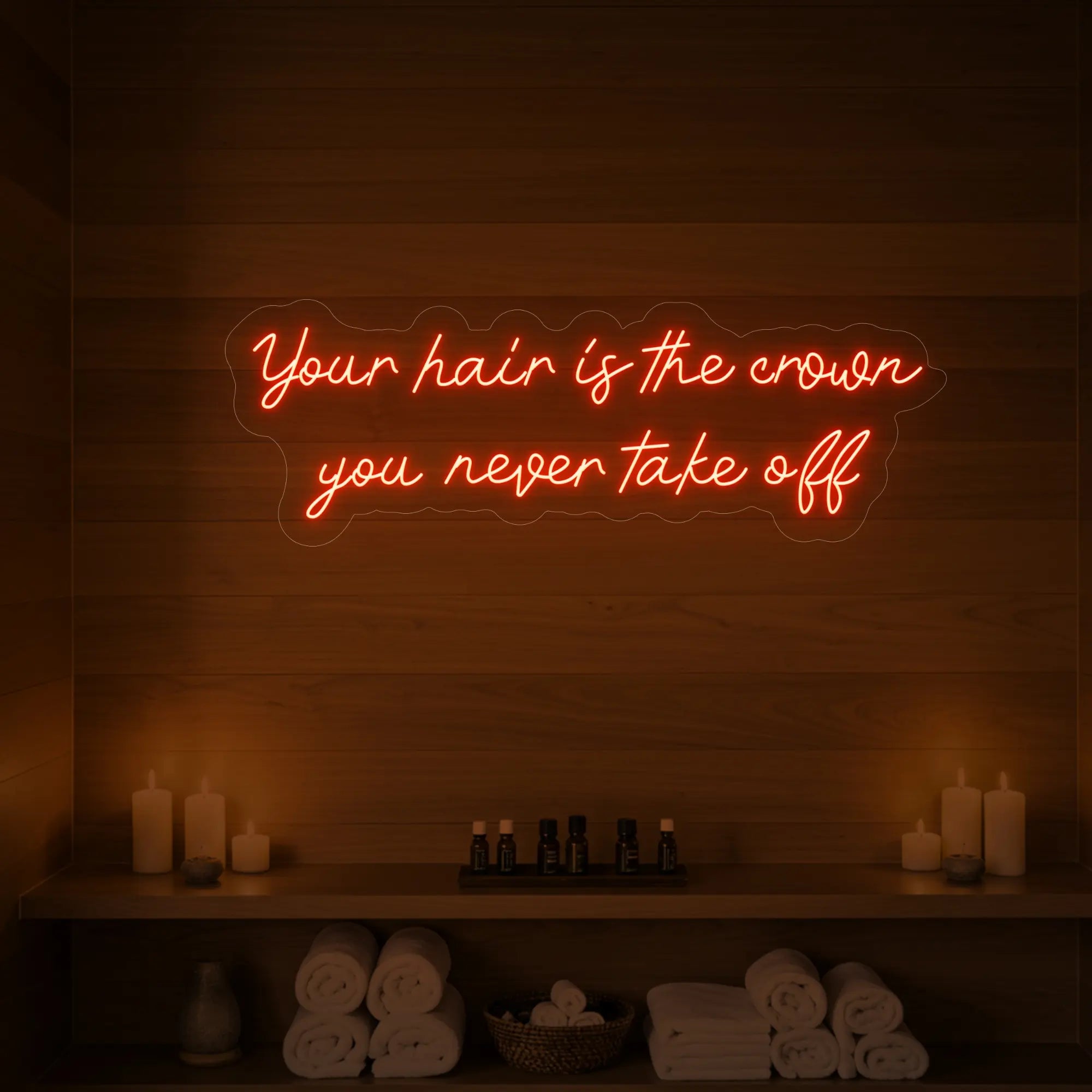 Photo of the 'Your Hair Is The Crown You Never Take Off' neon sign glowing in golden yellow against a styled interior wall.