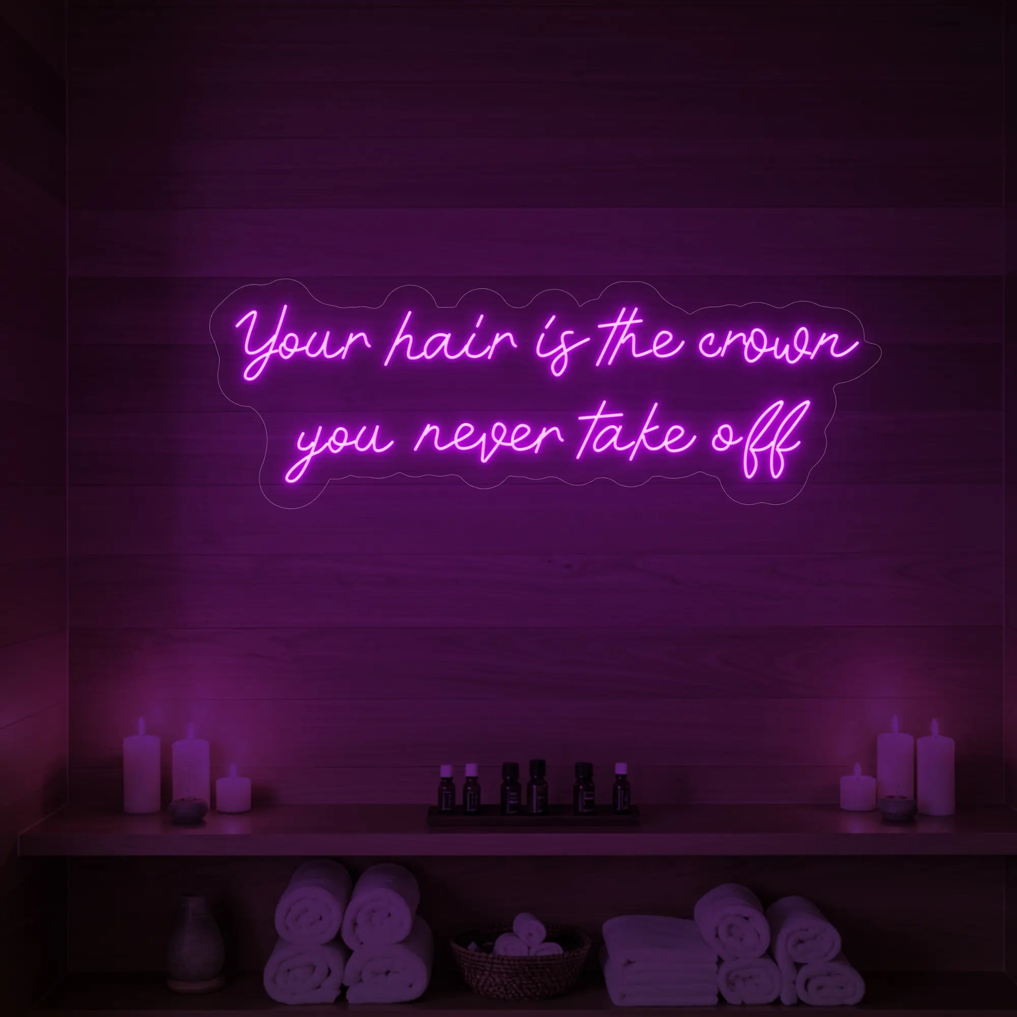 Photo of the 'Your Hair Is The Crown You Never Take Off' neon sign glowing in deep pink against a styled interior wall.