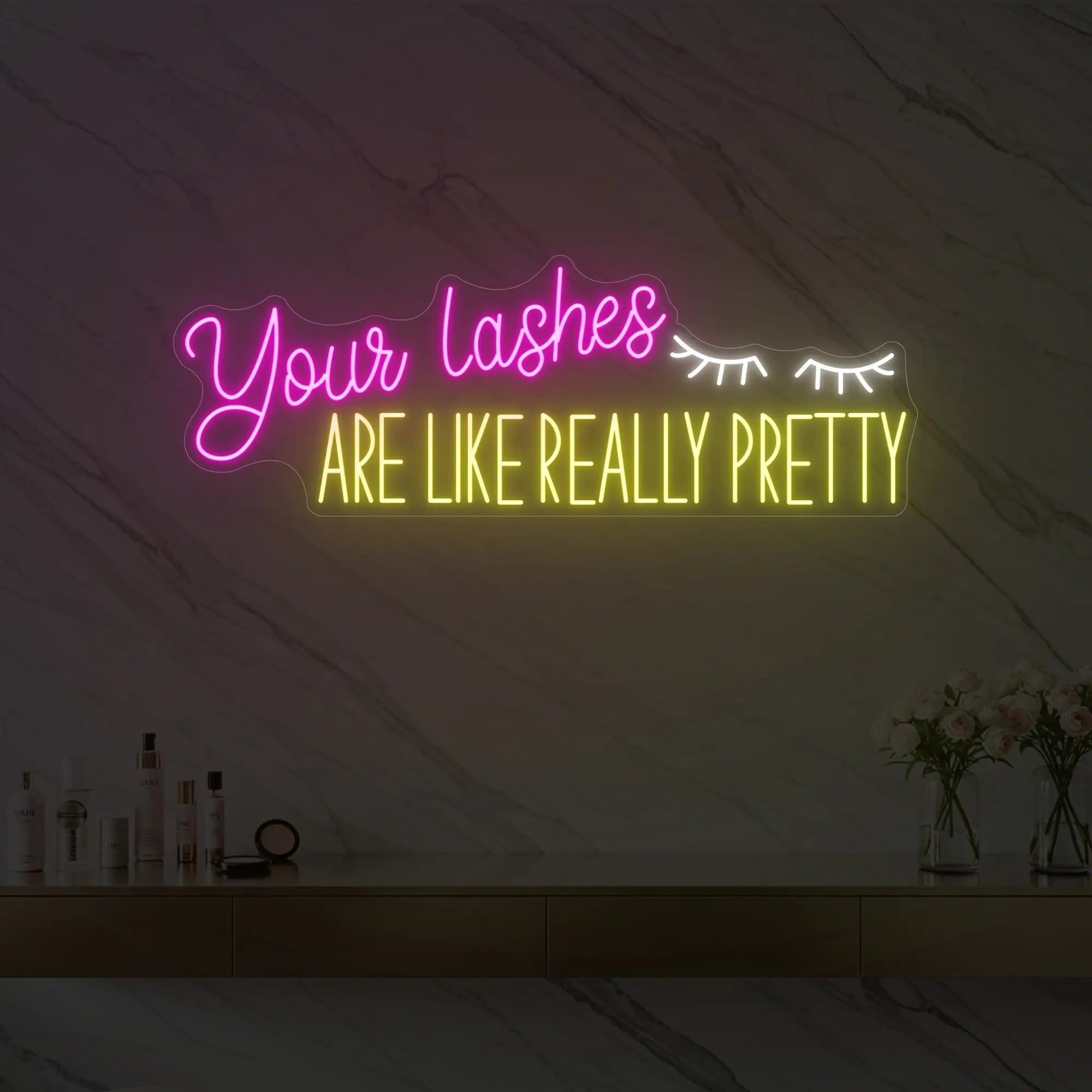 Photo of the 'Your Lashes Are Like Really Pretty' neon sign glowing in cool white, lemon yellow and light pink against a styled interior wall.