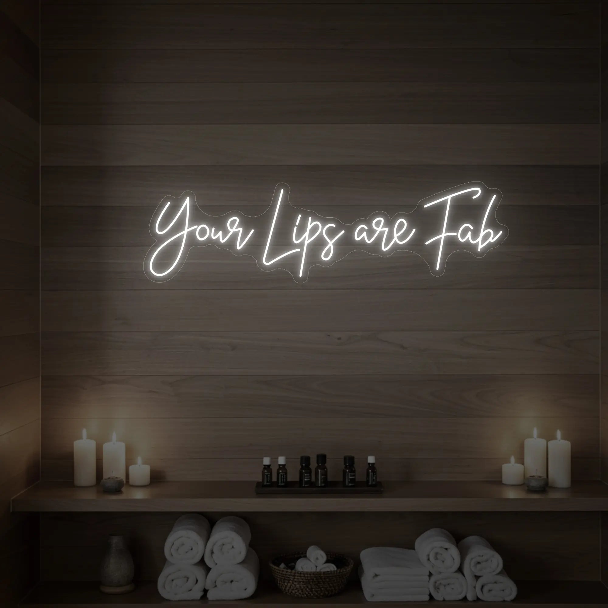 Photo of the 'Your Lips Are Fab' neon sign glowing in cool white against a styled interior wall.