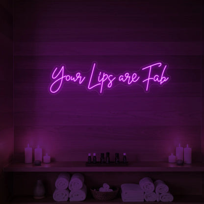 Photo of the 'Your Lips Are Fab' neon sign glowing in deep pink against a styled interior wall.