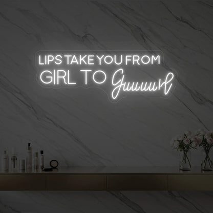 Photo of the 'LIPS TAKE YOU FROM GIRL TO Guuuurl' neon sign glowing in cool white against a styled interior wall.