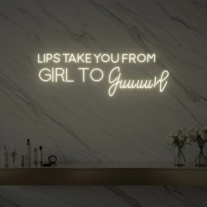 Photo of the 'LIPS TAKE YOU FROM GIRL TO Guuuurl' neon sign glowing in warm white against a styled interior wall.