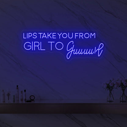 Photo of the 'LIPS TAKE YOU FROM GIRL TO Guuuurl' neon sign glowing in deep blue against a styled interior wall.