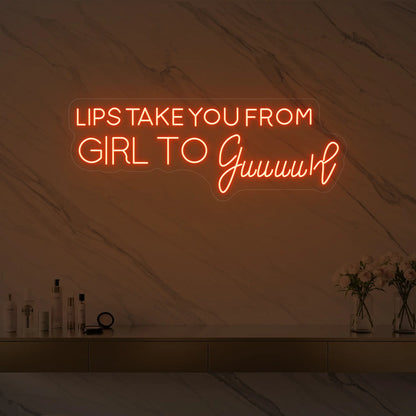 Photo of the 'LIPS TAKE YOU FROM GIRL TO Guuuurl' neon sign glowing in golden yellow against a styled interior wall.