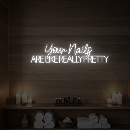Photo of the 'Your Nails Are Like Really Pretty' neon sign glowing in cool white against a styled interior wall.

