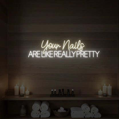 Photo of the 'Your Nails Are Like Really Pretty' neon sign glowing in warm white against a styled interior wall.

